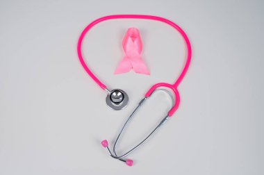 Beyaz arka planda pembe kurdele ve steteskop. Göğüs kanseriyle mücadele kavramı