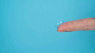 Mavi arka planda kontakt lens tutan kadın. Geniş Ekran