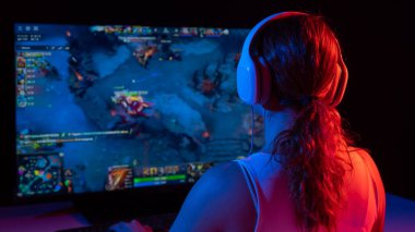 Kafkasyalı bir kadının karanlıkta neon ışıkta bilgisayar oyunu oynaması.