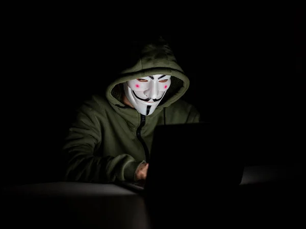 stock image June 5, 2022 Novosibirsk, Russia: Anonymous in a hood is typing on a laptop in the dark