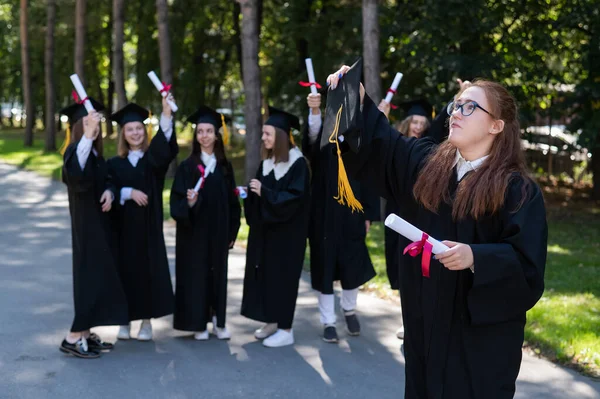 안경을 가운을 급우들 앞에서 여성의 초상화 야외에 졸업생들 — 스톡 사진