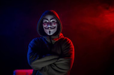 5 Haziran 2022 Novosibirsk, Rusya: Kırmızı-mavi dumanda Anonymous 'un kapüşonlu portresi