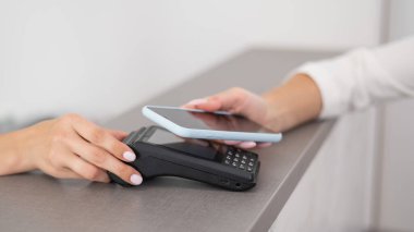 Bir kadın akıllı telefon tarafından kullanılan NFC 'nin bağlantısız ödemesini yapar.