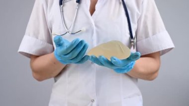 Bir plastik cerrah silikon göğüs implantlarının gücünü onları sıkarak gösterir.