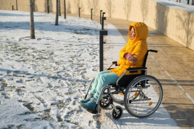 Tekerlekli sandalyedeki kadın kış parkında üşüyor.