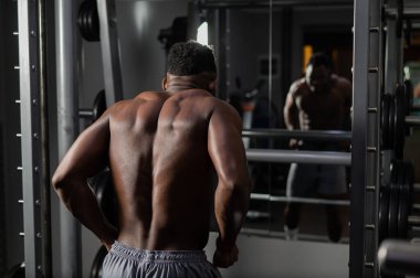 Yakışıklı afro-amerikalı adam spor salonunda sırt kaslarını gösteriyor.