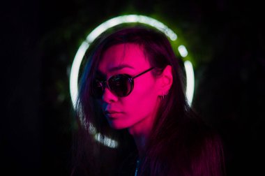 Neon ışıkta güneş gözlüğü takan Asyalı adamın portresi