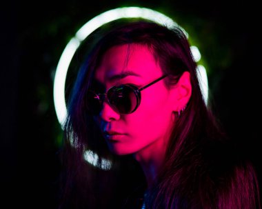 Neon ışıkta güneş gözlüğü takan Asyalı adamın portresi