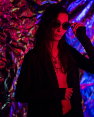 Stüdyoda neon ışıklı güneş gözlüklü bir transseksüel modelin portresi.