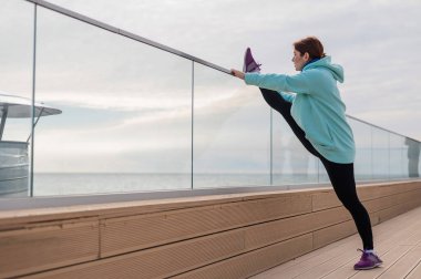 Tişörtlü beyaz bir kadın sicimin üzerinde esniyor.