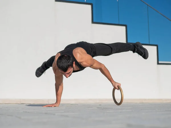Egy Férfi Fekete Sportruházatban Akrobatikus Kézen Áll Szabadban — Stock Fotó