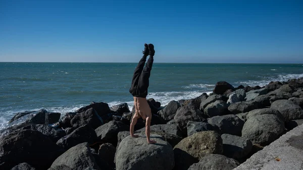 Bezkoszulowy Mężczyzna Stojący Rękach Skałach Nad Morzem — Zdjęcie stockowe