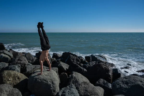 海のそばの岩の上に立つ白人の男 — ストック写真