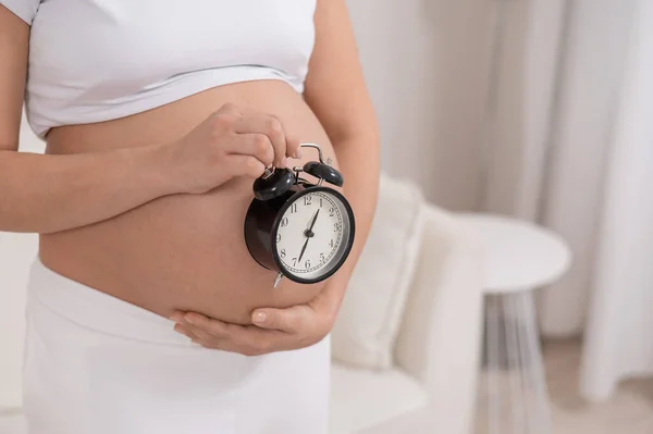 Een Zwangere Vrouw Met Een Naakte Buik Houdt Een Wekker — Stockfoto