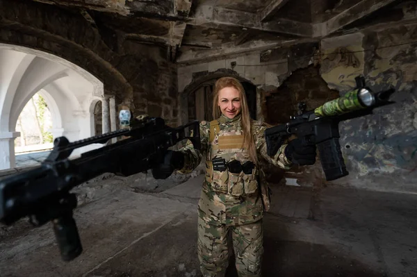 Caucasian woman in army uniform holding two machine guns