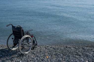 Kayalık bir sahilde boş bir tekerlekli sandalye.