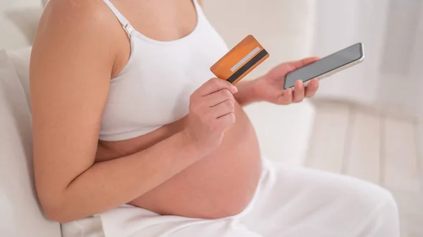 妊婦さんがスマホとクレジットカードを持っています オンラインショッピングのコンセプト — ストック写真