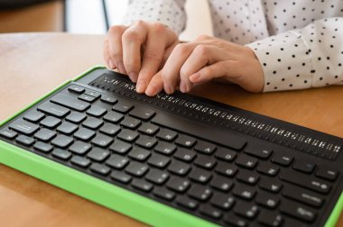 Kör bir kadın Braille ekranı ve klavyesi olan bir bilgisayar kullanıyor. Özel aygıt