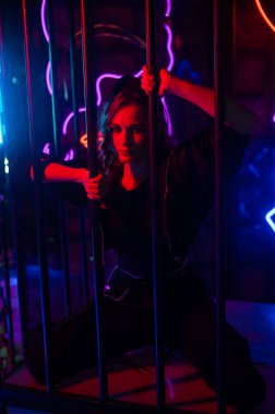 Neon bir stüdyoda kafeste beyaz bir kadın.