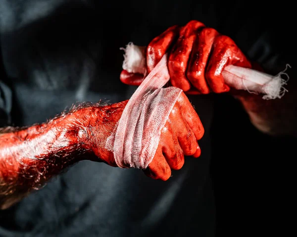 一个浑身是血的男人用绷带包住双手 — 图库照片