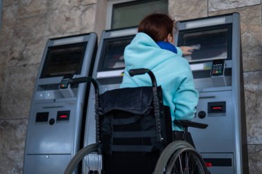 Tekerlekli sandalyedeki beyaz bir kadın tren istasyonundaki self servis kasasına ulaşamaz. Ulaşılması zor bir ortam