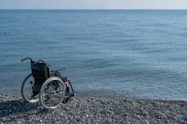 Kayalık bir sahilde boş bir tekerlekli sandalye.