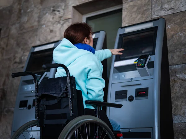 Tekerlekli sandalyedeki beyaz bir kadın tren istasyonundaki self servis kasasına ulaşamaz. Ulaşılması zor bir ortam