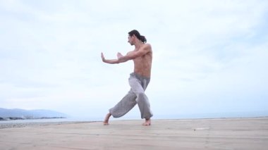 Kafkasyalı, uzun saçlı, dışarıda qigong antrenmanı yapan bir adam.