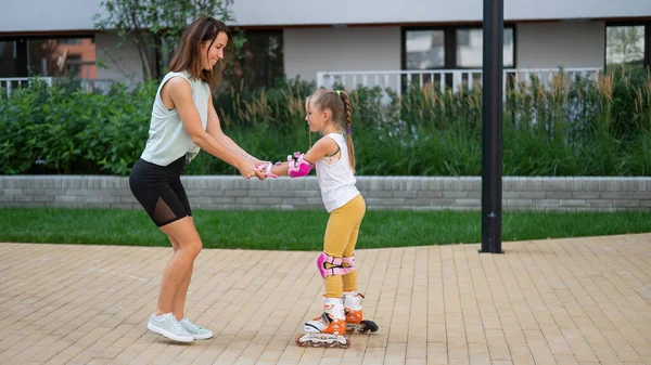 Mother and daughter go in for sports outdoors. Caucasian woman and little girl are engaged in fitness at the stadium