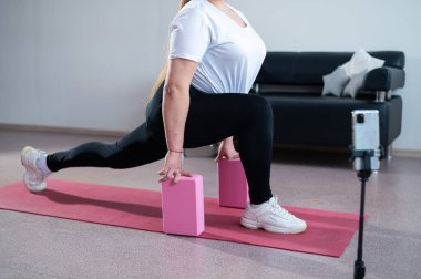 Genç Artı Boyutlu Kadın İnternet 'te esniyor. Esnek kız yoga yapıyor ve internetten dizüstü bilgisayarda ders izliyor..