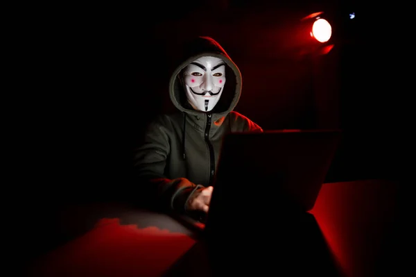 2022年6月5日俄罗斯诺沃西比尔斯克 无名氏头罩在黑暗的红灯下在笔记本电脑上打字 — 图库照片