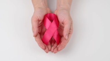 Kadın ellerini açar ve beyaz masaya kırmızı bir kurdele koyar. AIDS 'le mücadelenin sembolü
