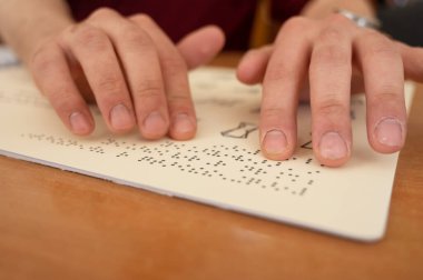 Körler alfabesi kitabı okuyan görme engelli bir adam.
