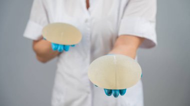 Doktor plastik cerrah farklı göğüs implantları gösteriyor.