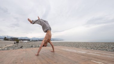 Çakıl taşlı plajda ters takla atan beyaz bir adam.