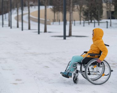 Tekerlekli sandalyedeki kadın kış parkında dinleniyor.