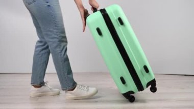 Kadın valizini yere koyar ve yukarıdan atlar. Kız bavulu test ediyor.