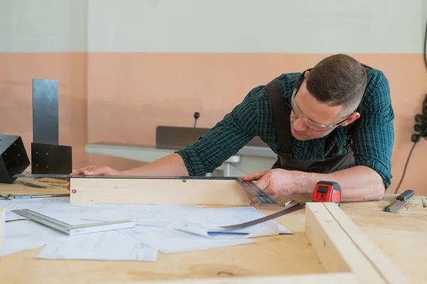 stock image Carpenter measures wooden planks in the workshop