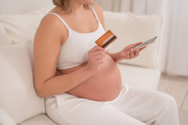 妊婦さんがスマホとクレジットカードを持っています オンラインショッピングのコンセプト — ストック写真