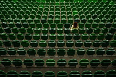 A caucasian woman stands on an empty tribune of a stadium. Female cheerleader