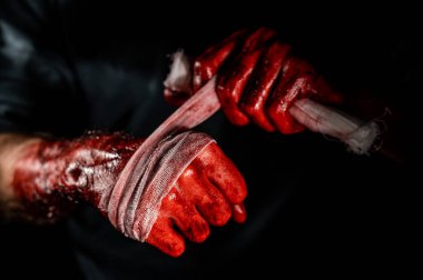 Kanla kaplı bir adam ellerini bandajlıyor.
