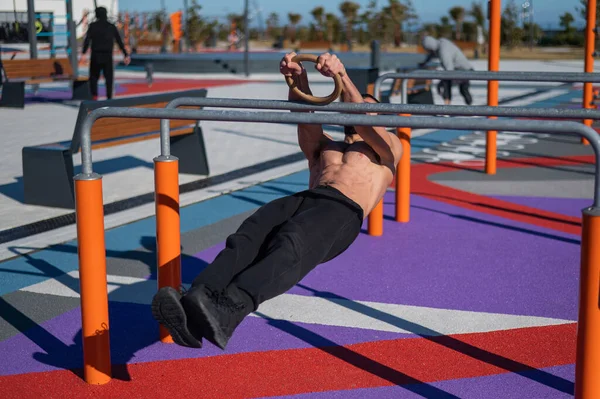 stock image Shirtless man doing horizontal balance on parallel bars at sports ground