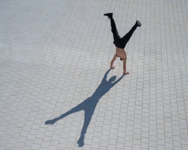 Tişörtsüz bir adam dışarıda elini kolunu sallayarak yürüyor. Yukarıdan görüntüle