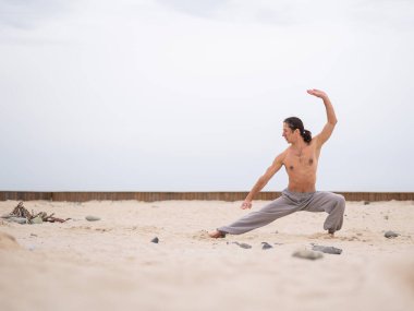 Kafkasyalı, uzun saçlı, dışarıda qigong antrenmanı yapan bir adam.