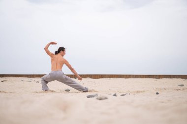 Kafkasyalı, uzun saçlı, dışarıda qigong antrenmanı yapan bir adam.