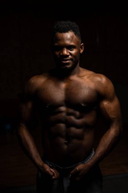 Karanlık bir stüdyoda çıplak gövdesi olan Afro-Amerikan bir adamın portresi. Kaslı adam.