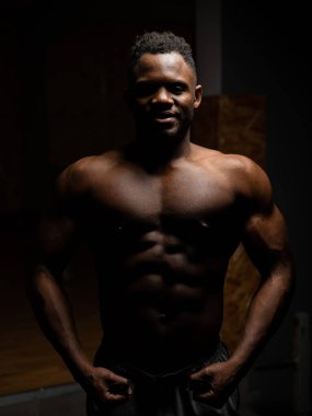 Karanlık bir stüdyoda çıplak gövdesi olan Afro-Amerikan bir adamın portresi. Kaslı adam.