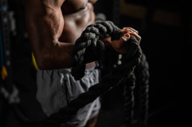 Kaslı Afrikalı Amerikalı adam spor salonunda iple poz veriyor.