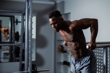 Yakışıklı Afro-Amerikan adam spor salonunda paralel bar egzersizi yapıyor.