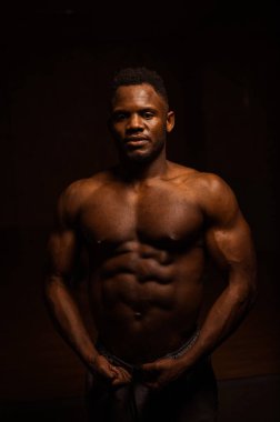 Karanlık bir stüdyoda çıplak gövdesi olan Afro-Amerikan bir adamın portresi. Kaslı adam.